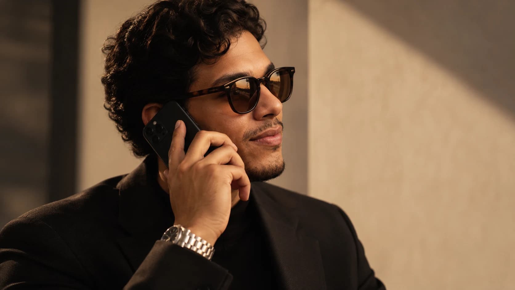 José Filho em retrato editorial com blazer preto, óculos escuros e luz dourada.